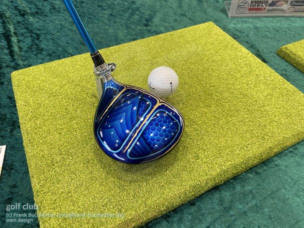 Blauer Golfschläger mit detailliertem Muster, daneben ein weißer Golfball.