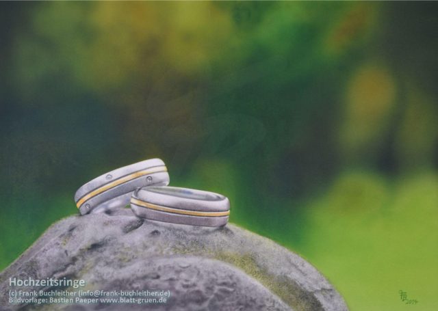Zwei Eheringe auf einem grauen Stein mit verschwommenem, grünem Hintergrund.