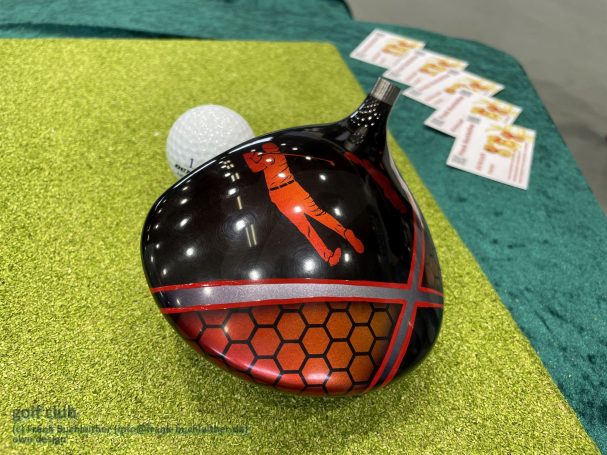 Schwarze Golfschläger mit rotem Design, daneben ein Golfball.
